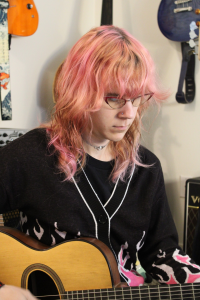 Heather Knopf looks down at the fingerboard as she plays an acoustic guitar.