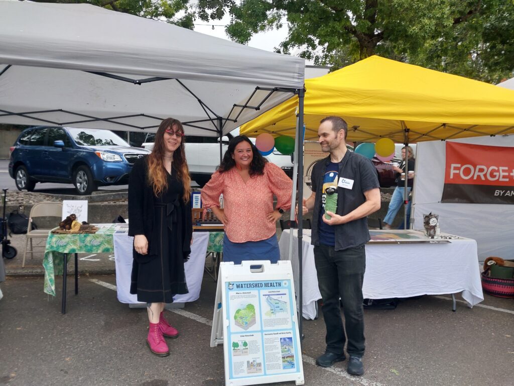 D4C staff and the Westside Watershed manager stand and laugh in front of their booths.