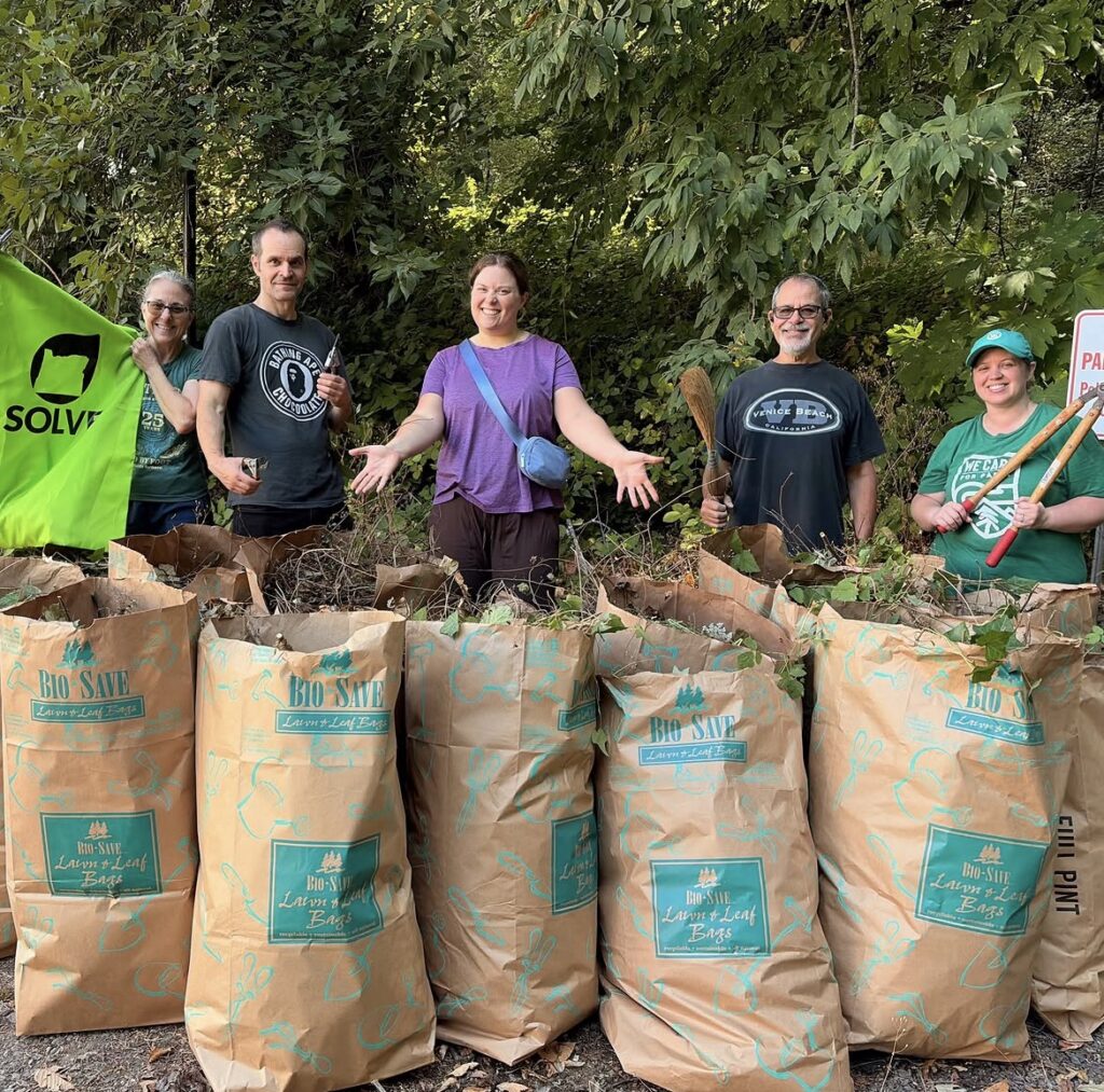 Volunteers stand over their many bags of collected English Ivy